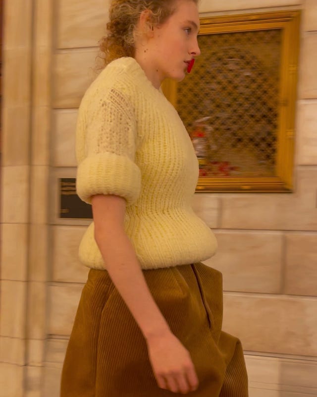 individual walking while wearing a white sweater and brown pants individual walking while wearing a white sweater and brown pants