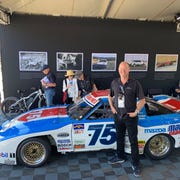 tommy kendall stands in front of his mazda rx 7 race car