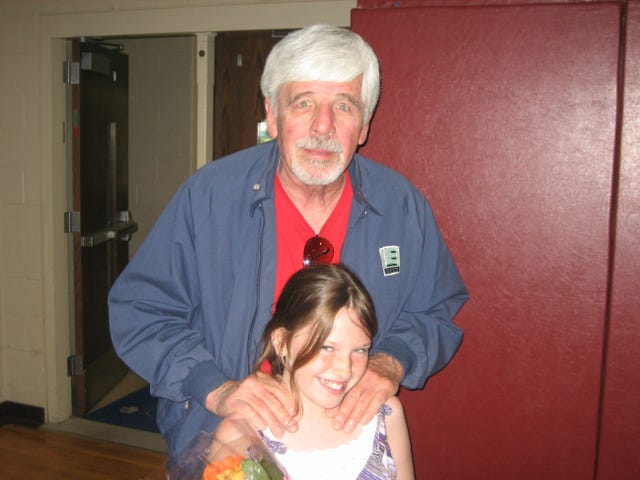 an adult standing behind a child both are smiling