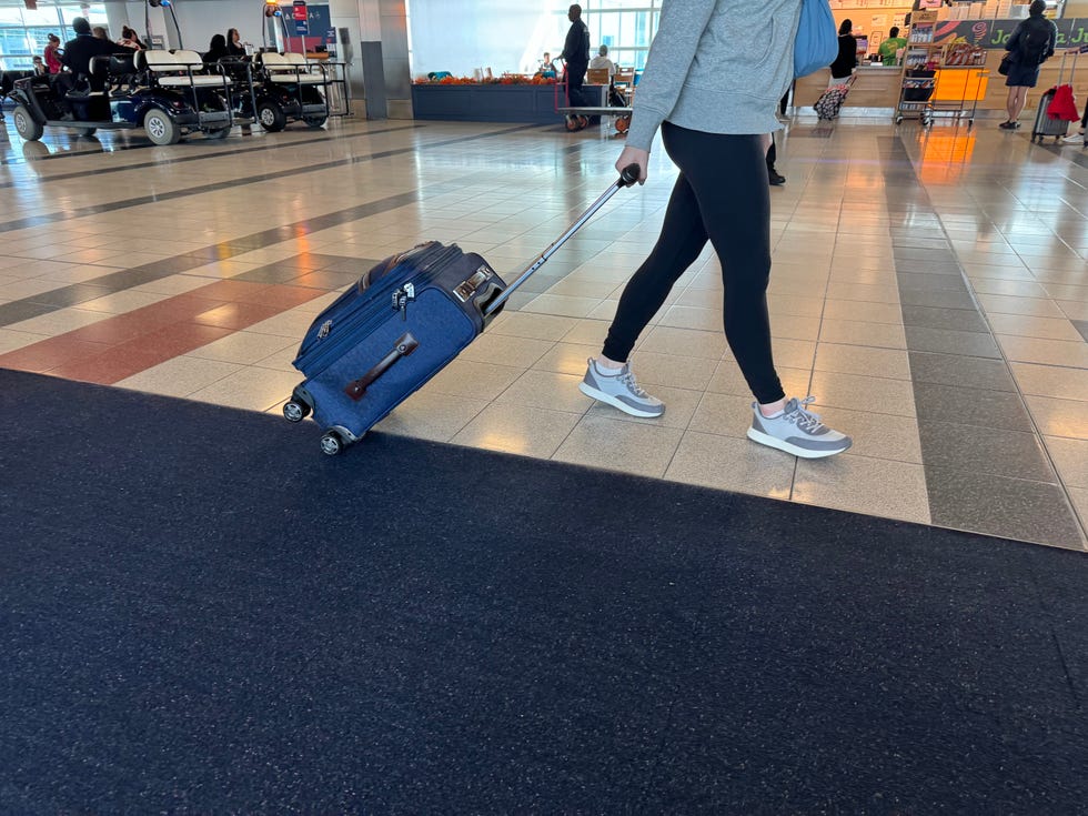 someone pulling a travelpro suitcase through an airport