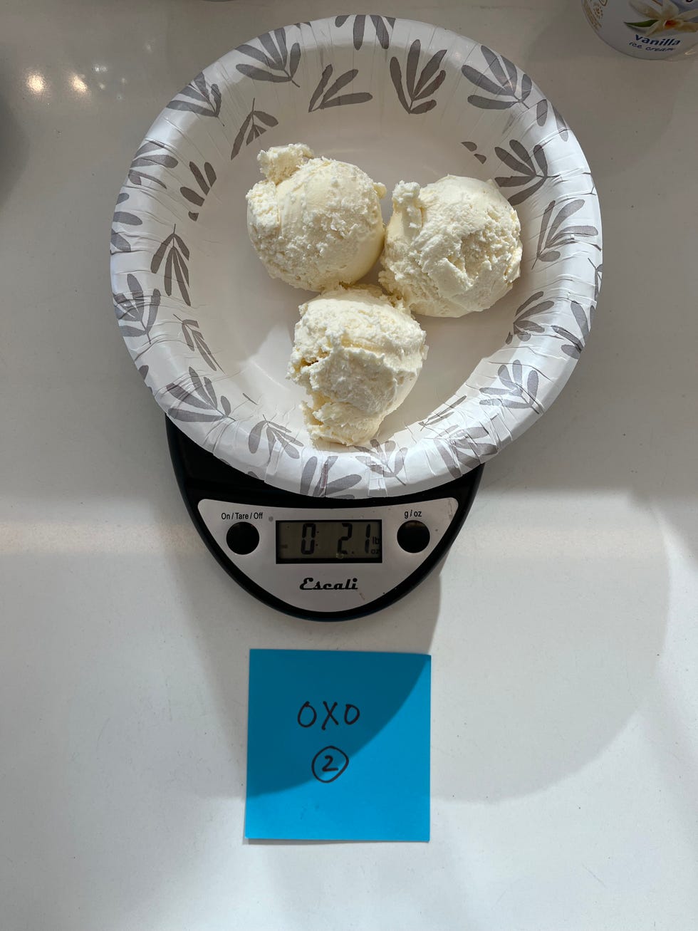 three scoops of ice cream on a paper plate placed on a scale with a sticky note nearby