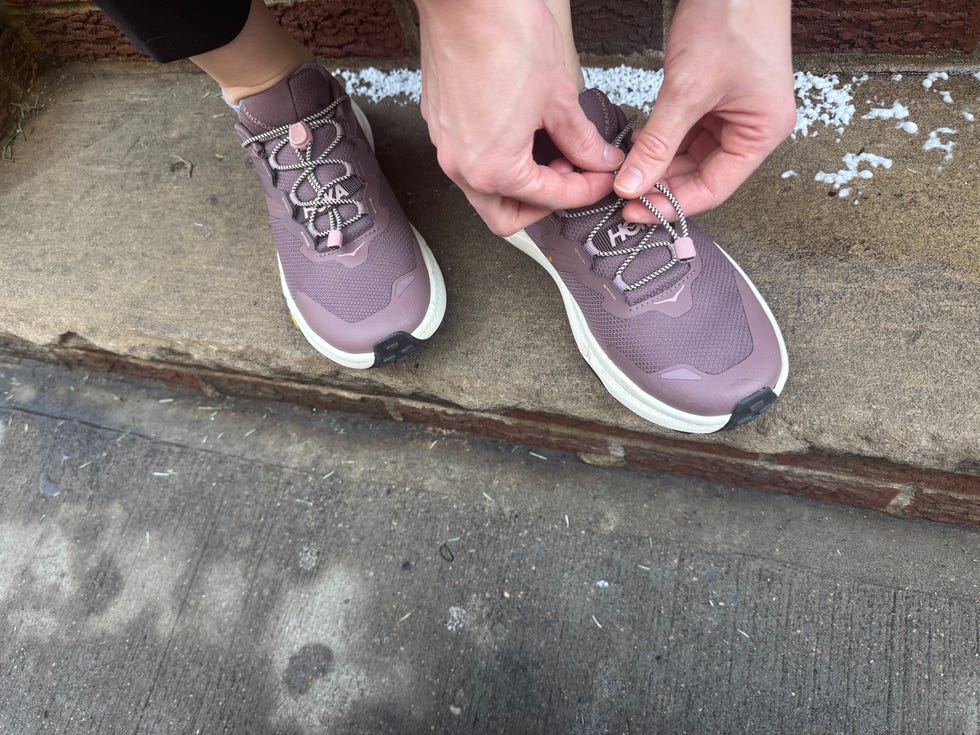 a person lacing up hoka transport slip on shoes