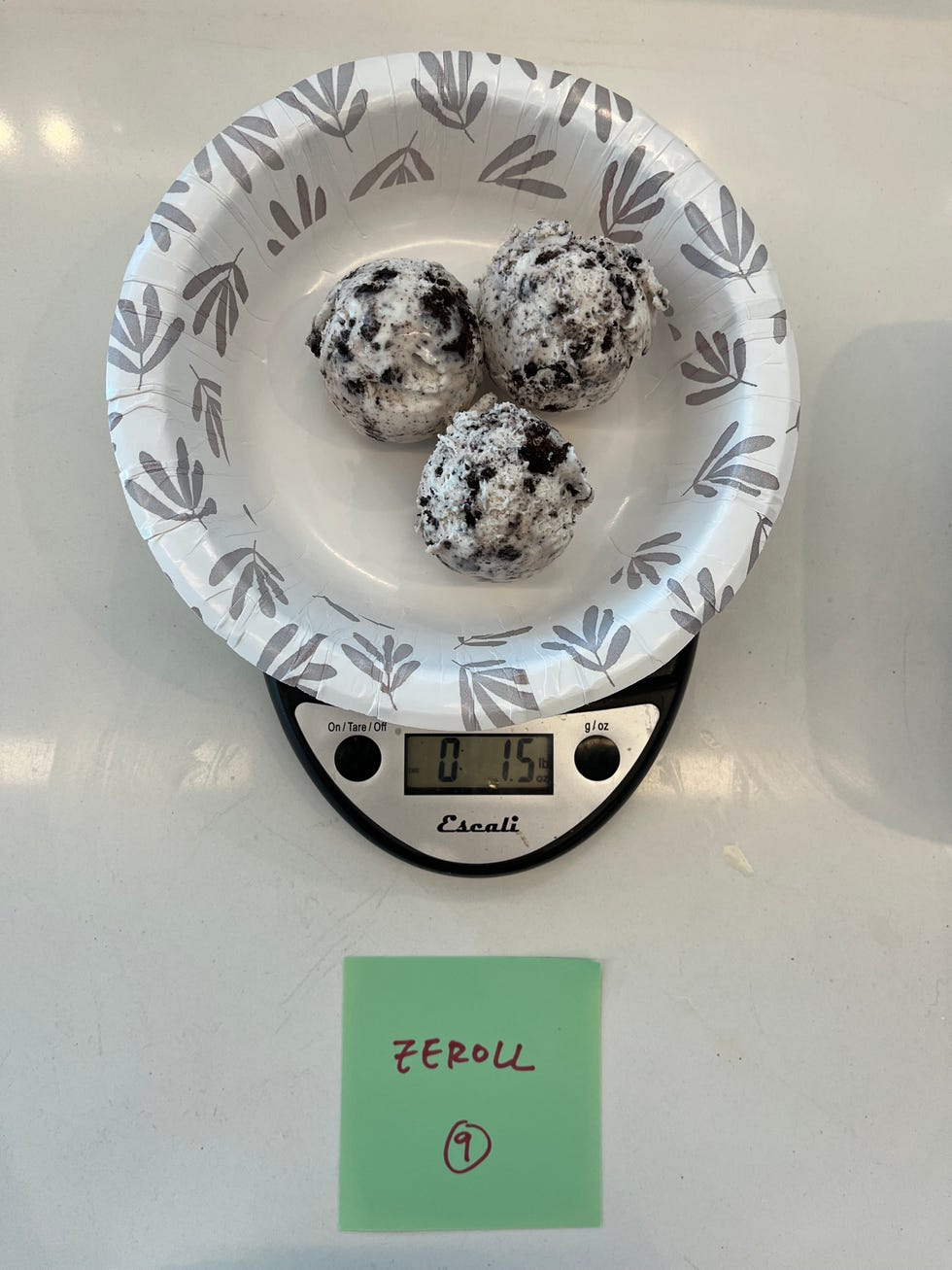 three scoops of cookies and cream ice cream in a paper bowl
