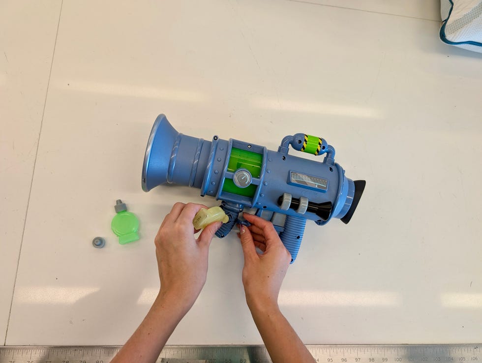 a person assembling a toy fart blaster with colorful components on a table