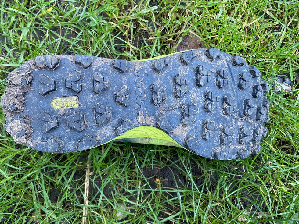 sole of a trail running shoe showing traction lugs and dirt