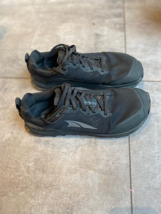 black athletic shoes with laces placed on a tiled surface