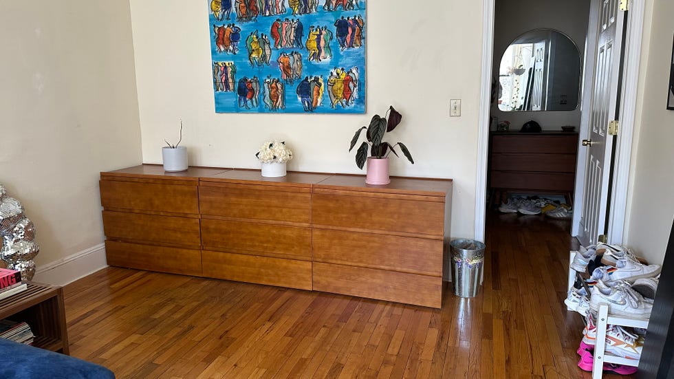 a thuma dresser in the living room with a blue painting above it