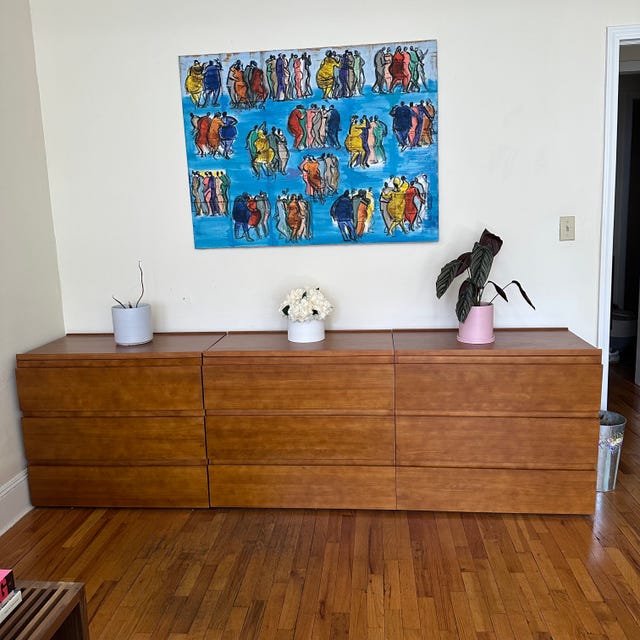 a thuma dresser in the living room with a blue painting above it