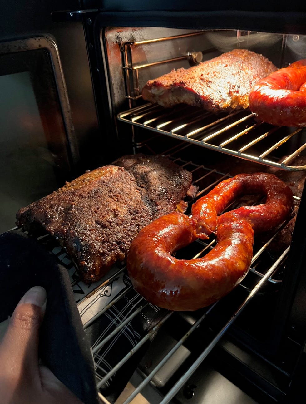 meat being smoked in an oven with a hand holding a towel