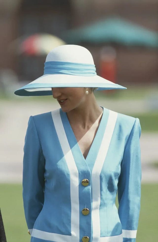 eine Person, die ein blaues Outfit mit weißen Streifen und einen großen Sonnenhut trägt