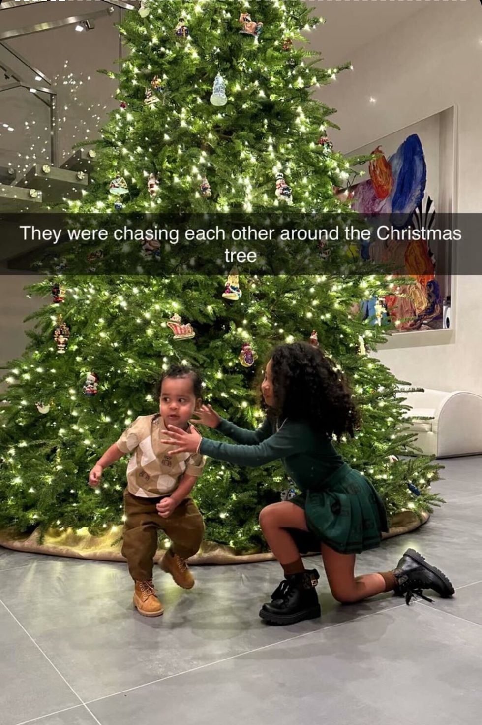 a person and a child dancing in front of a christmas tree