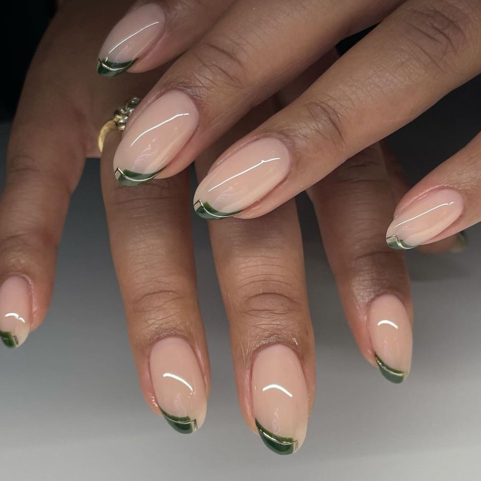 a hand with a manicure featuring green and gold tips