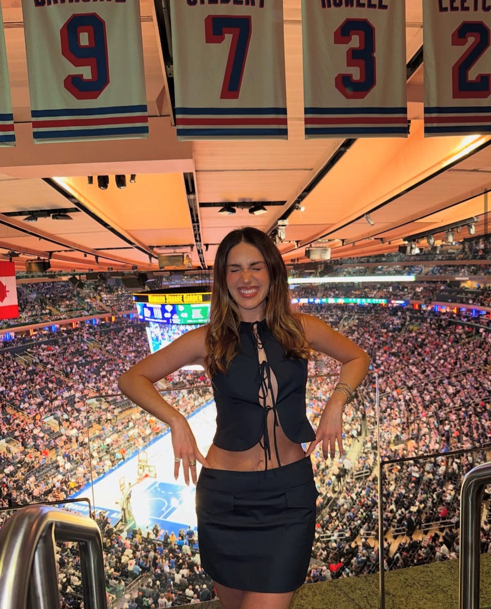 uma pessoa posando em uma arena de basquete com camisas expostas no alto