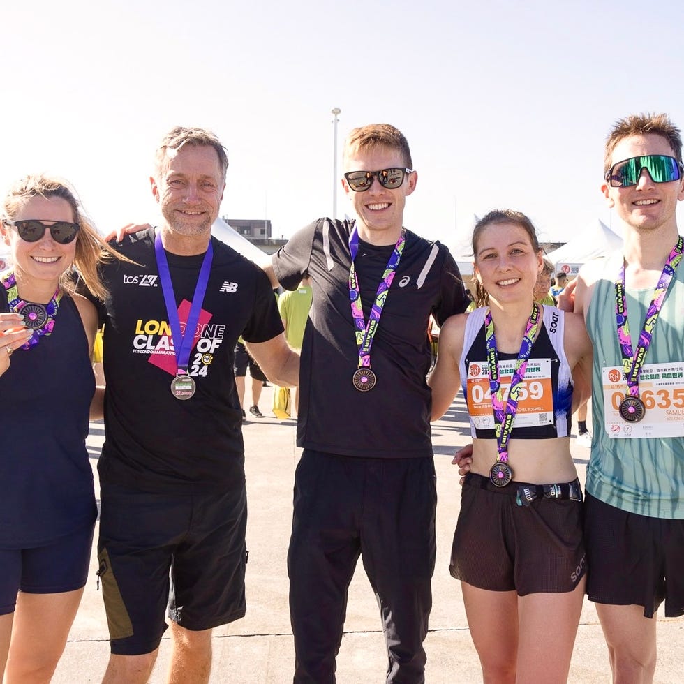 five individuals celebrating an athletic achievement with medals and race bibs