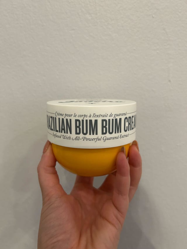 a hand holding a tub of brazilian bum bum cream