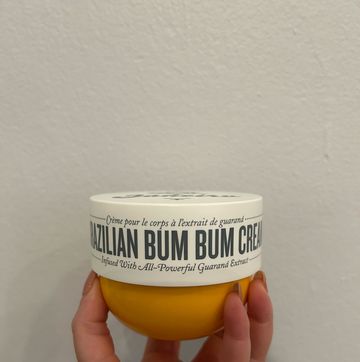 a hand holding a tub of brazilian bum bum cream