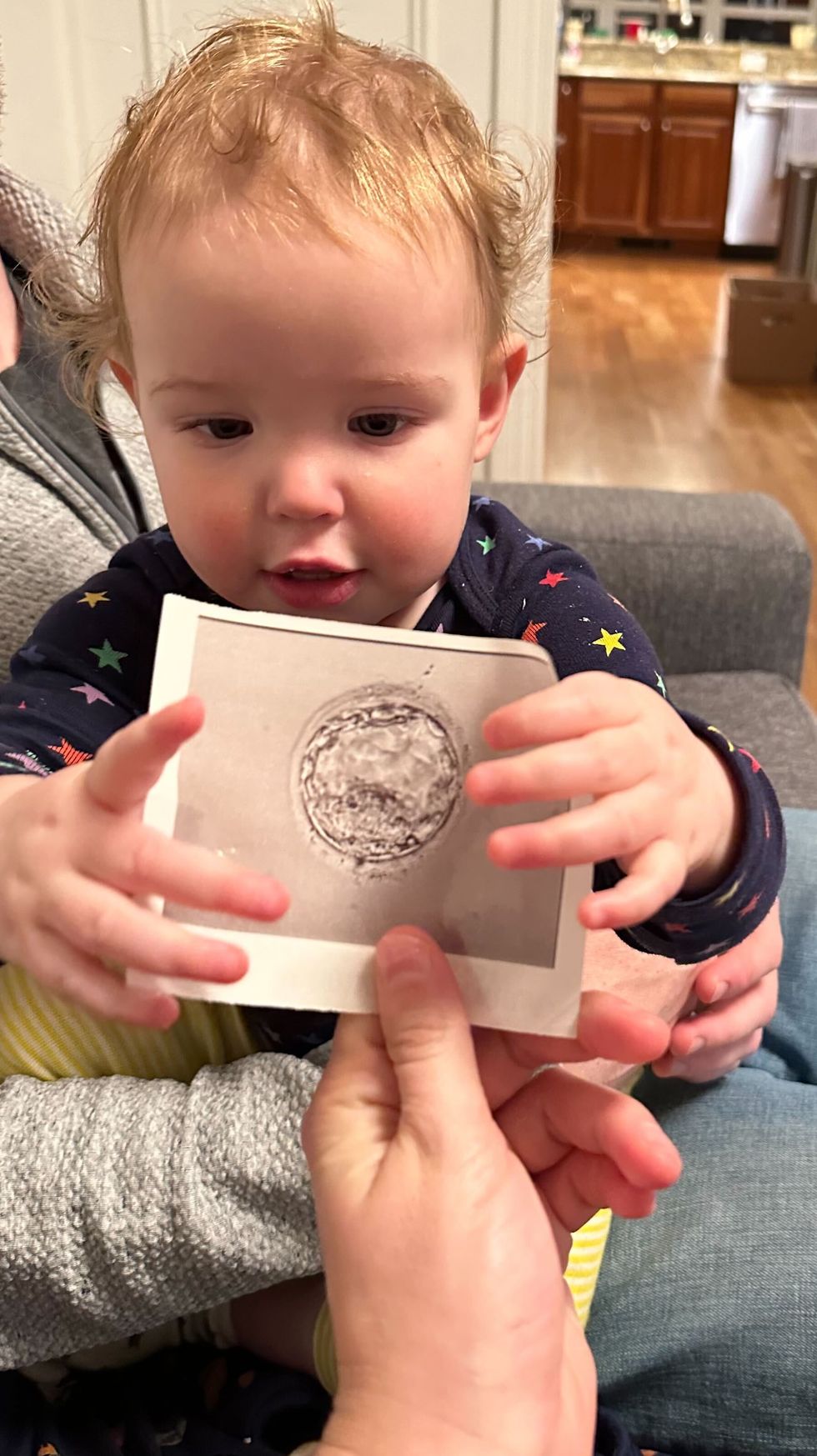 a baby holding up a paper photo