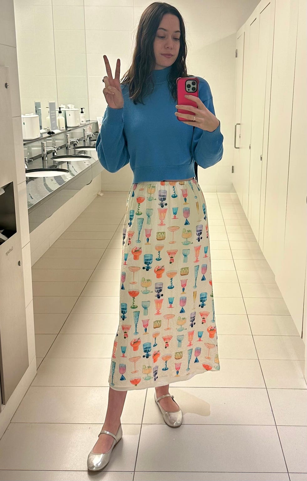 gh analyst wearing a blue sweater and cocktail glass print skirt from nuuly taking a mirror selfie