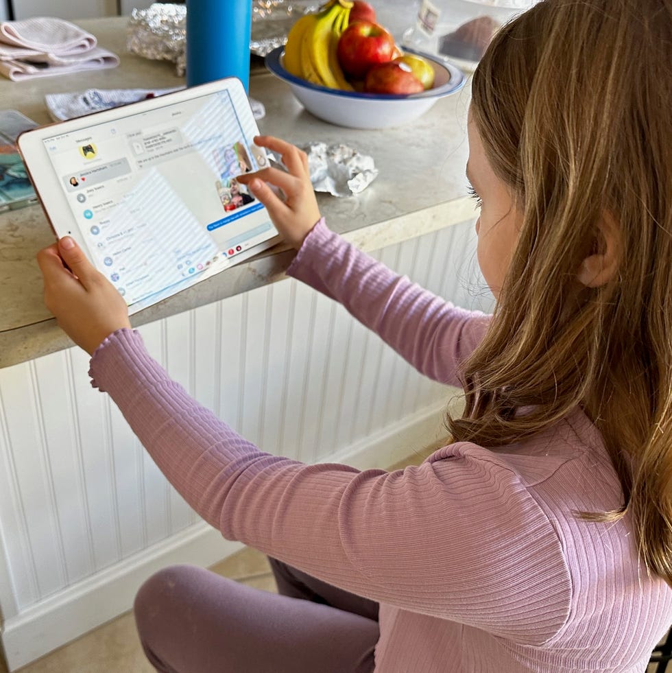 a child using an ipad, one of the best tablets for kids child using a tablet in a kitchen setting, part of a good housekeeping story on the best kids tablets