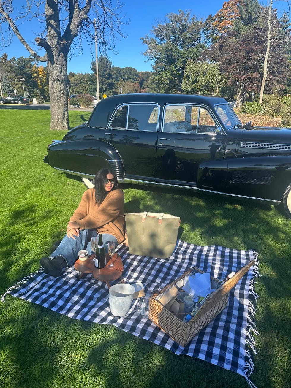 a person sitting on a blanket in front of a car