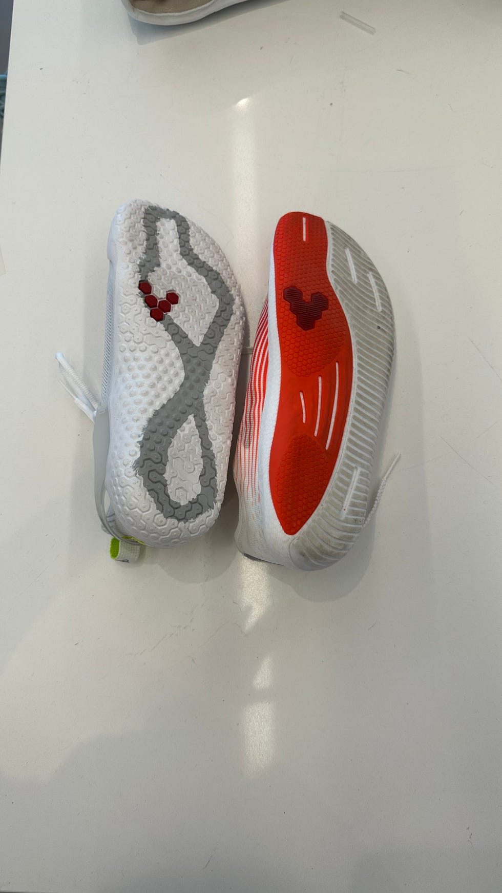 the bottom soles of two vivobarefoot sneakers on a white table