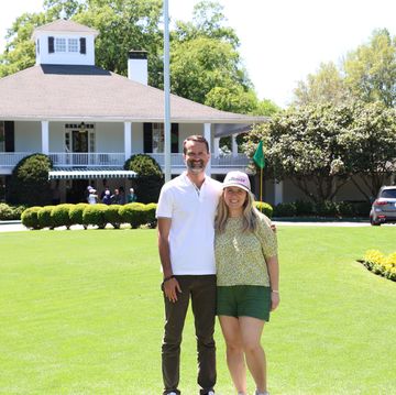 a couple posing in front of the clubhouse at augusta national golf club during the masters tournament