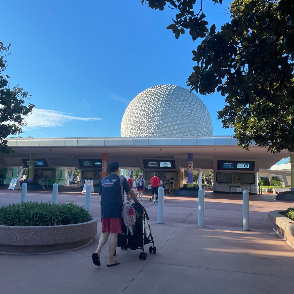 disney world epcot park entrance in the early morning a person walking with a stroller