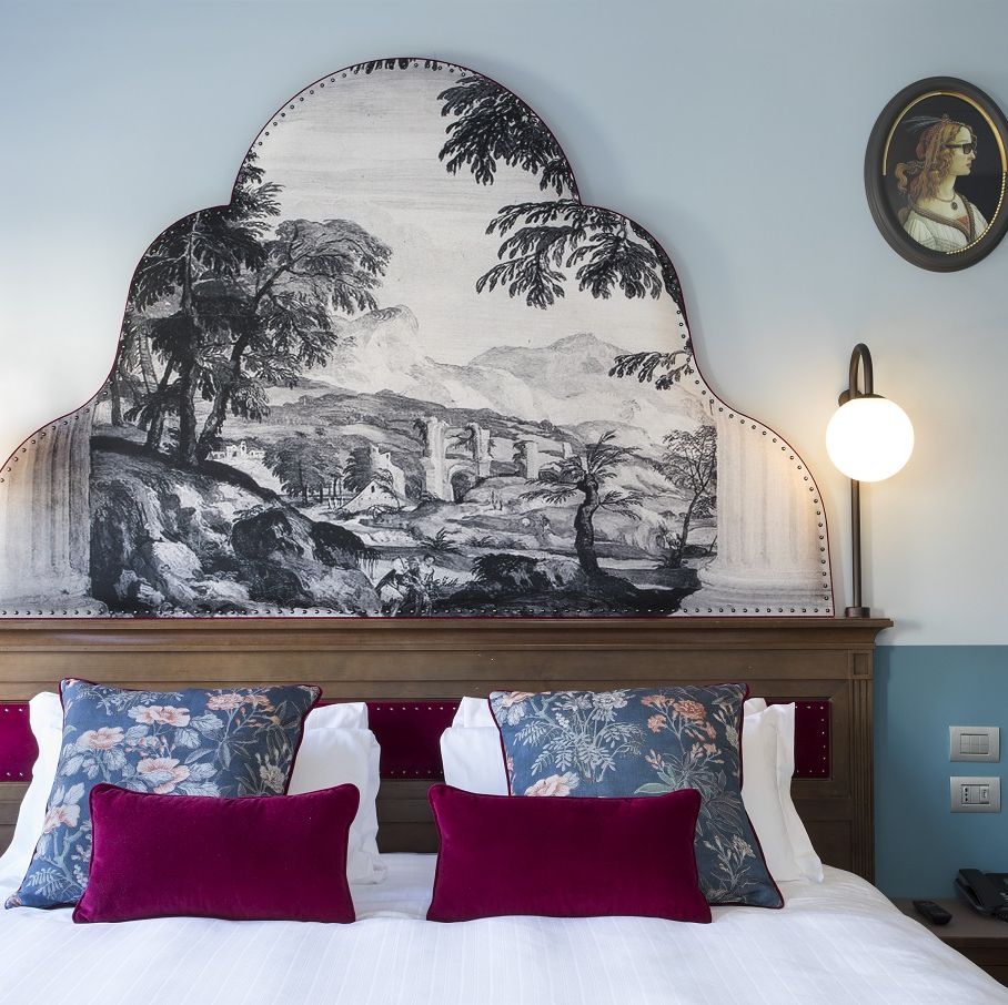 a bed with pillows and a painting on the wall