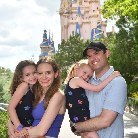 a family smiling in front of cinderella castle at magic kingdom park