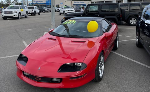 red 90s camaro on a dealer lot
