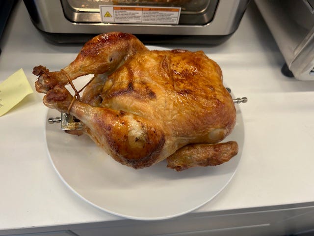 a rotisserie chicken on spit on a plate