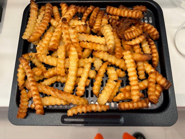 a tray holds a generous serving of crinkle cut fries, showcasing a golden brown surface with various lengths and a slightly irregular shape several fries appear crisp and well cooked while a few are darker possibly indicating different cooking times the fries are spread out to show their texture and patterns