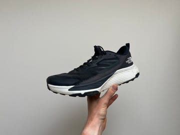 a person's hand holding a black and white shoe