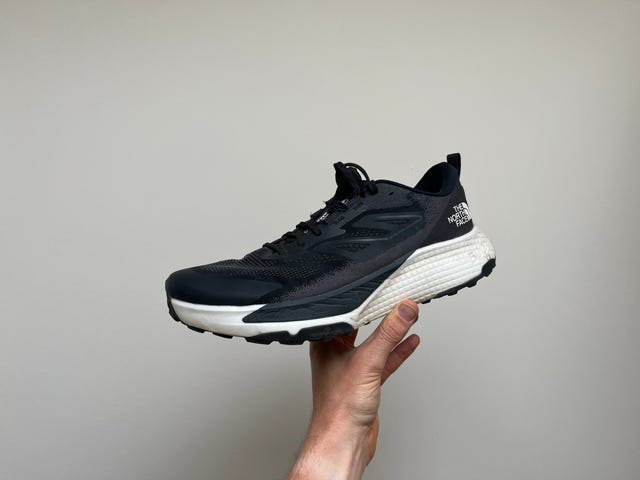 a person's hand holding a black and white shoe