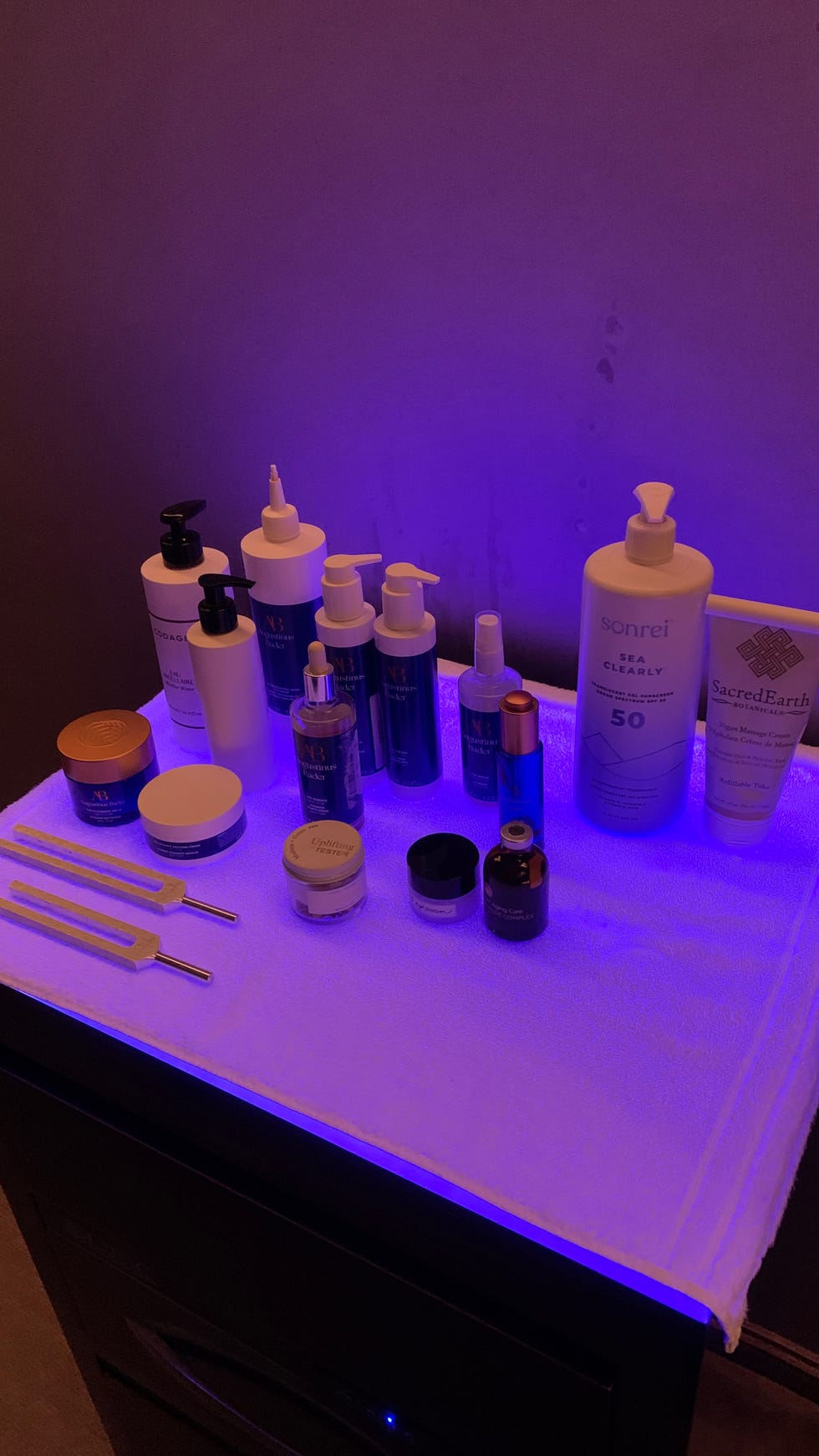 a display of skincare products and tools arranged on a white towel under a blue light