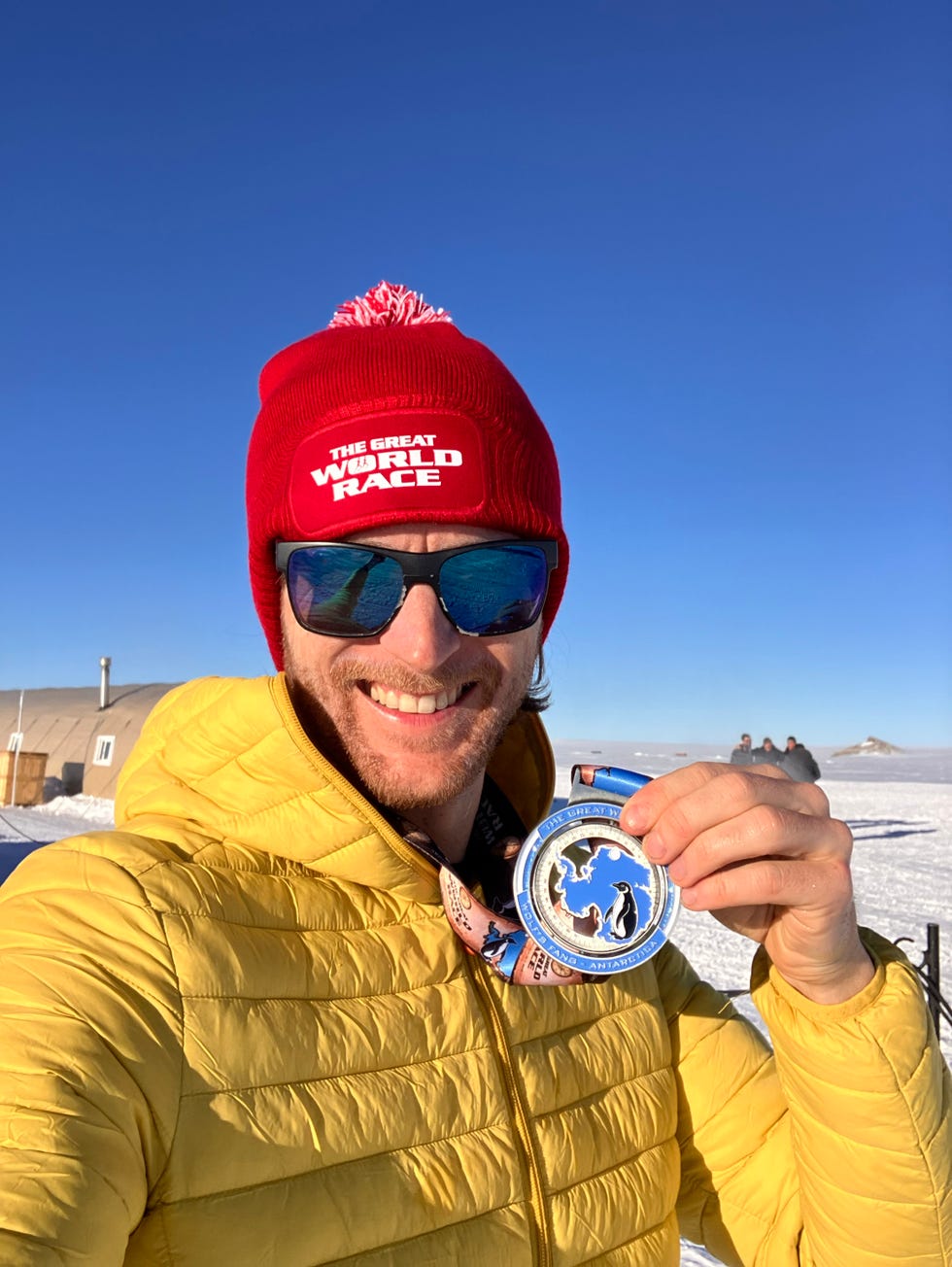 a person holding a medal wearing a red winter hat and a yellow coat