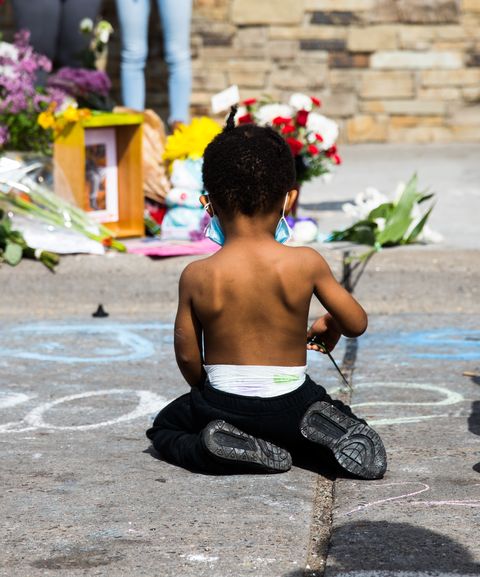 a little boy kneels ﻿in minneapolis, minnesota, ﻿near where george floyd was murdered