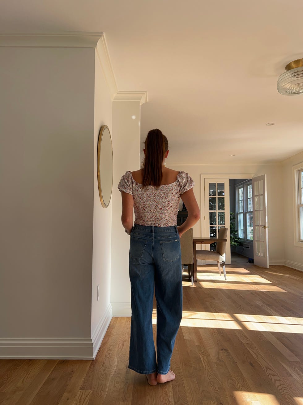 woman wearing floral shirt and jeans in a living room