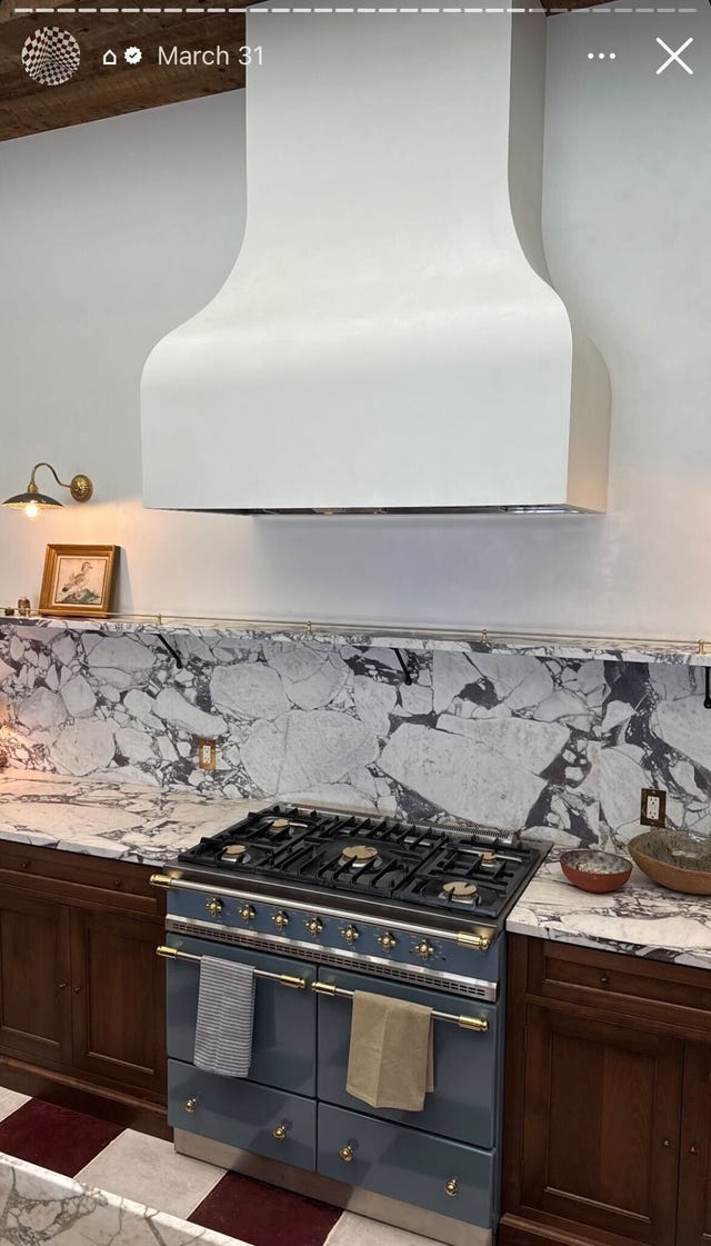 kitchen with red and white tile, dark cabinets, blue range, and bold marble