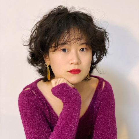 a headshot of the designer rui zhou of the brand rui wearing a magenta fuzzy sweater with small cutouts and large gold earrings