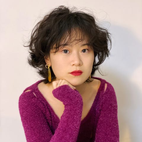 Rui Zhou a headshot of the designer rui zhou of the brand rui wearing a magenta fuzzy sweater with small cutouts and large gold earrings