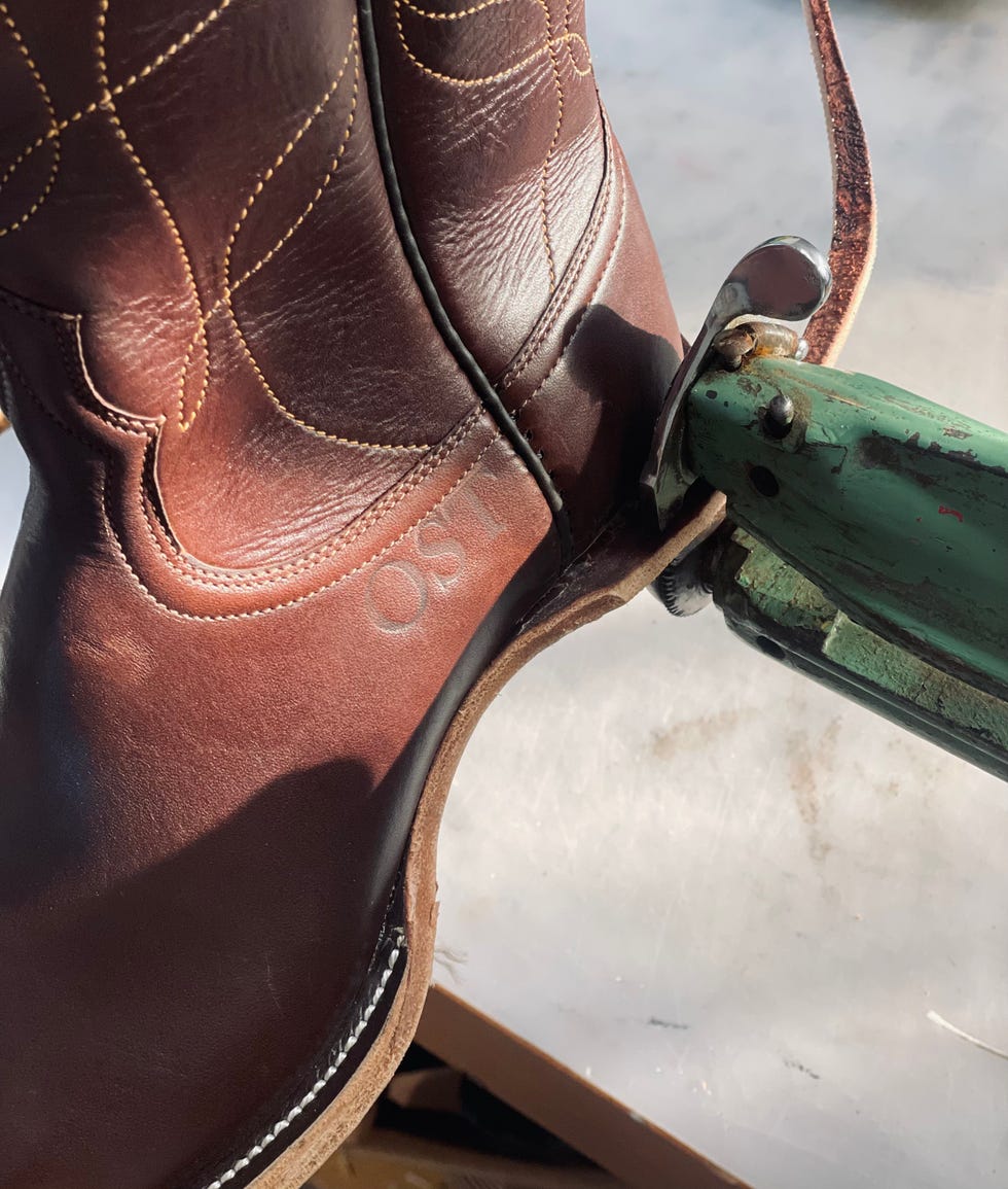 brown leather cowboy boot with stitching partially on a sewing machine