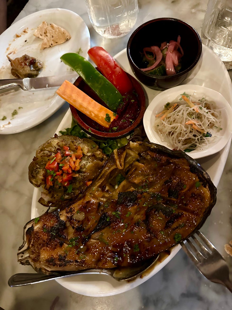 grilled eggplant dish with various sides and garnishes