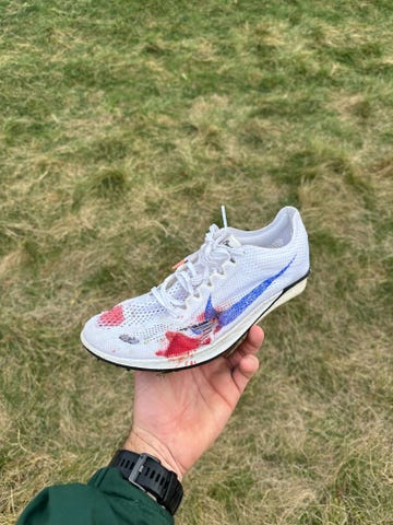 a hand holding a damaged white athletic shoe with a colorful design