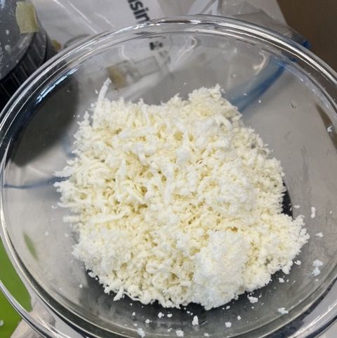 a bowl of shredded mozzarella being weighed
