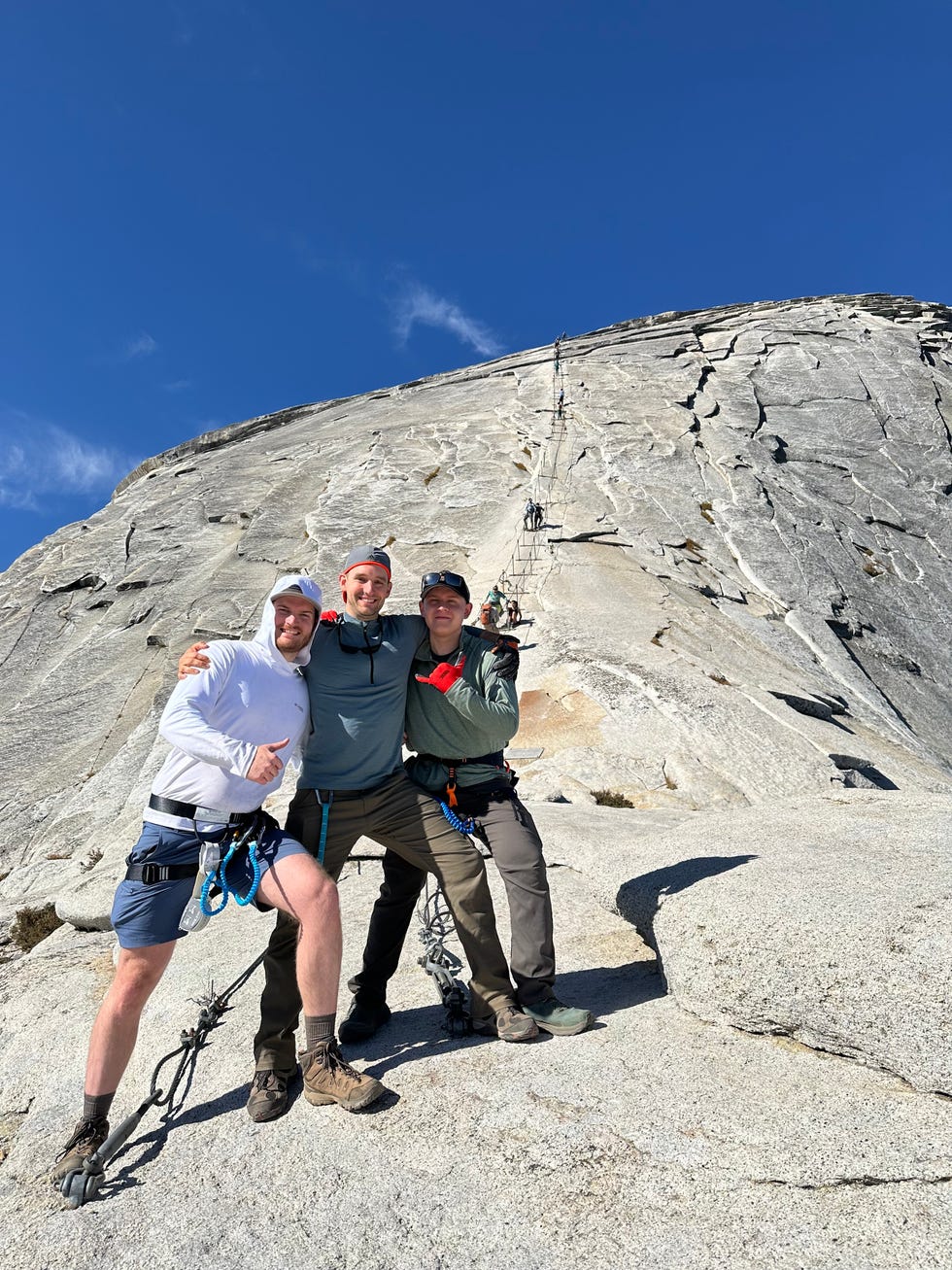 Three climbers posing near a rocky cliff face while ascending