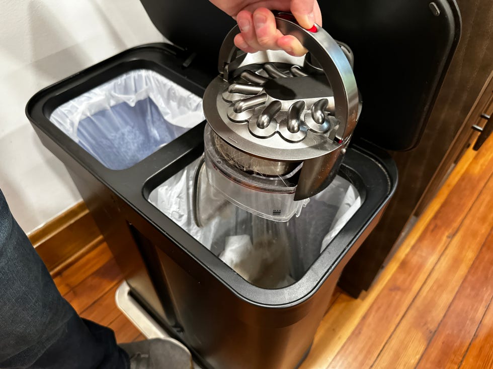 the author emptying the dyson 360 vis nav dust cup into a trash can
