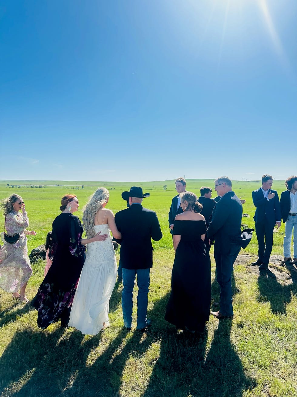 Paige Drummond Wedding Repearsal Individuals gathered outside for a ceremony in a grassy field