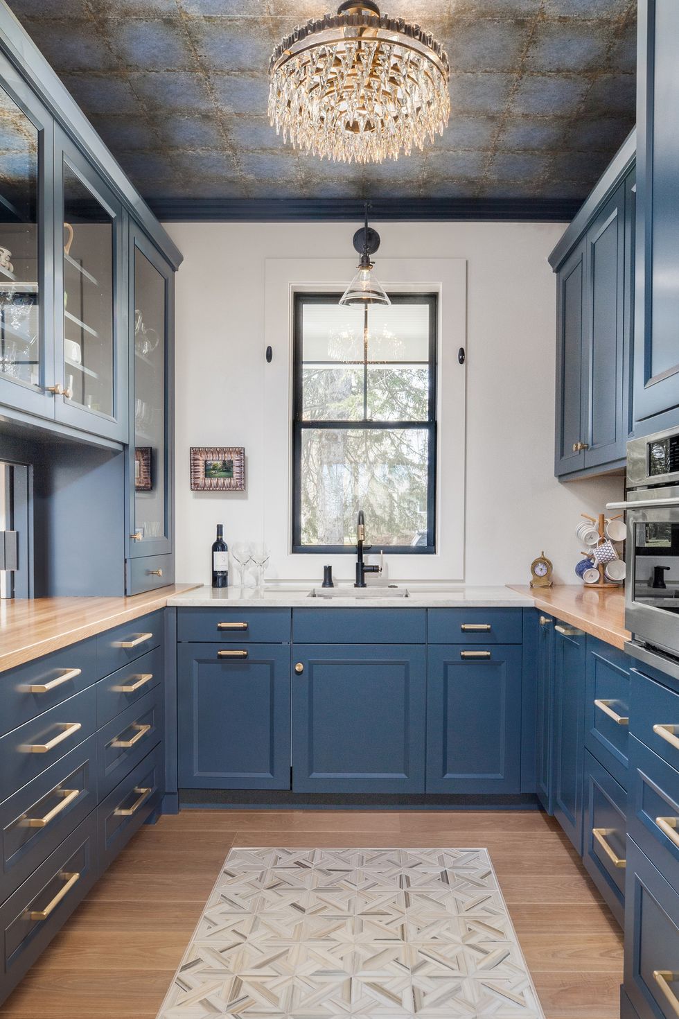 bold butlers pantry with wallpaper ceiling and blue cabinets