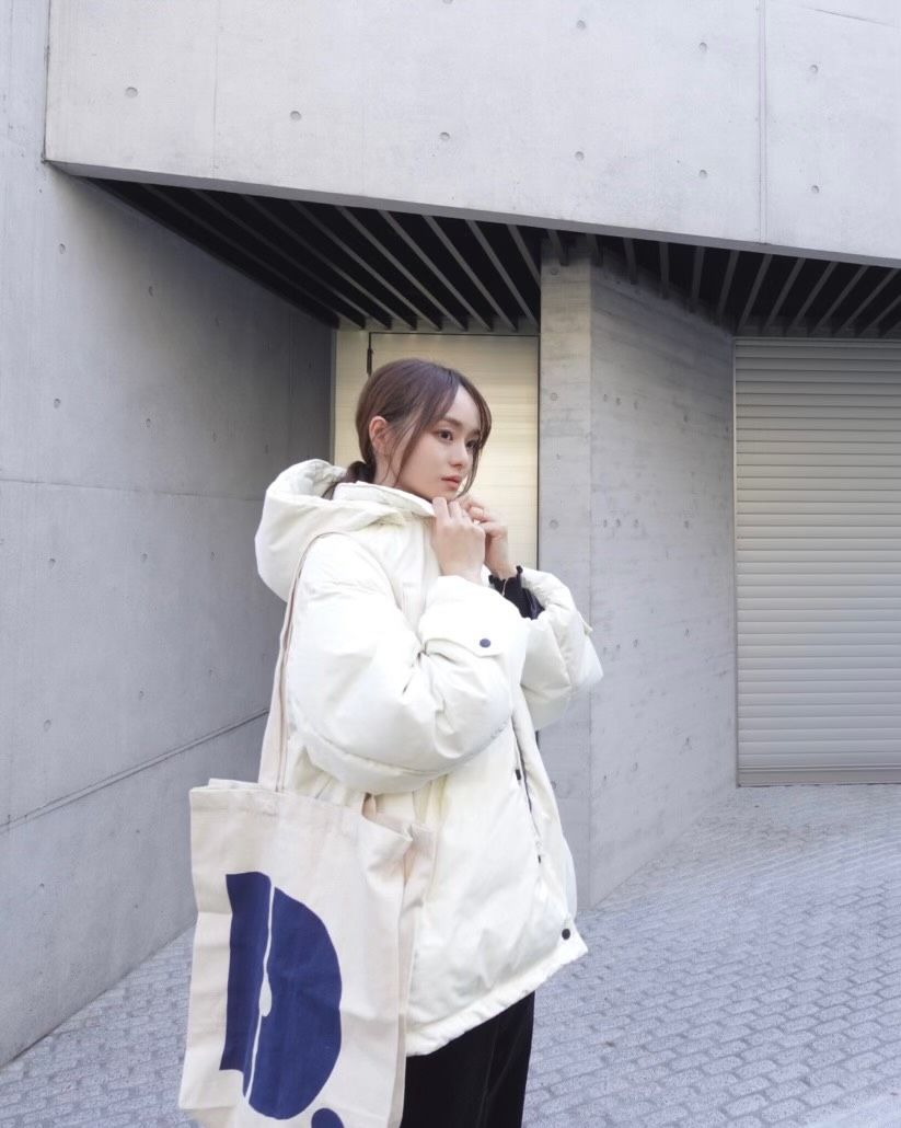 a woman in a white coat holding a white bag